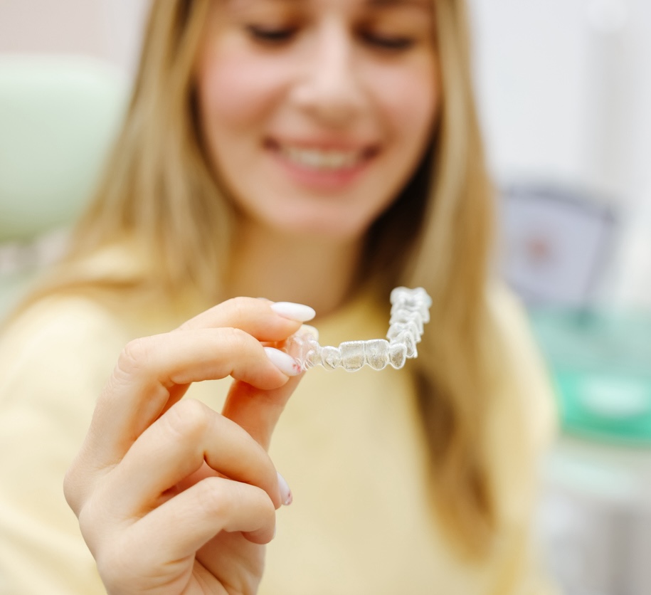 Woman holding her bottom clear aligner in front of her