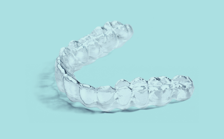 Close up of a sleek uLab® clear aligner on a light blue surface